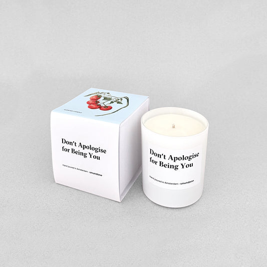 White candle “Don’t Apologise for Being You” next to matching box with tomato illustration.